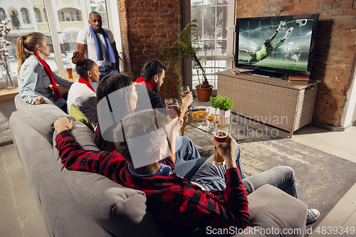 Image of Excited group of people watching sport match at home