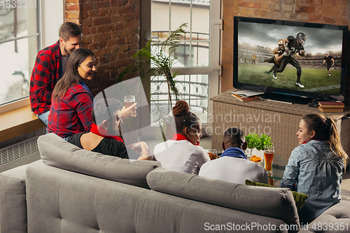 Image of Excited group of people watching sport match at home
