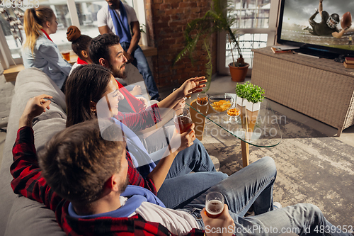 Image of Excited group of people watching sport match at home