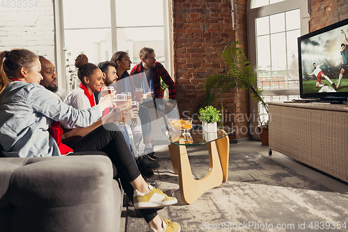 Image of Excited group of people watching sport match at home