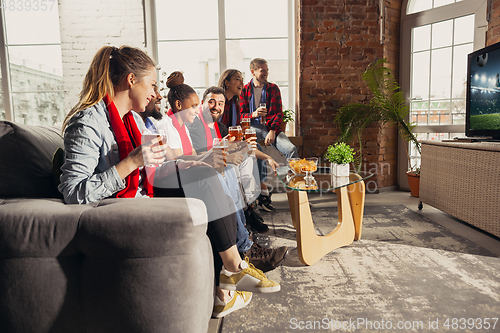 Image of Excited group of people watching sport match at home