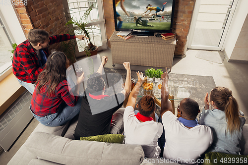 Image of Excited group of people watching sport match at home
