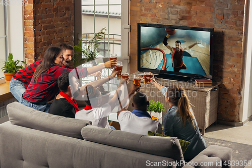 Image of Excited group of people watching sport match at home