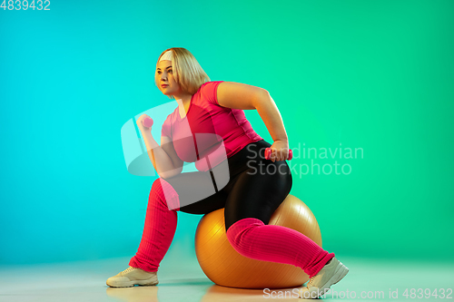 Image of Young caucasian plus size female model\'s training on gradient green background