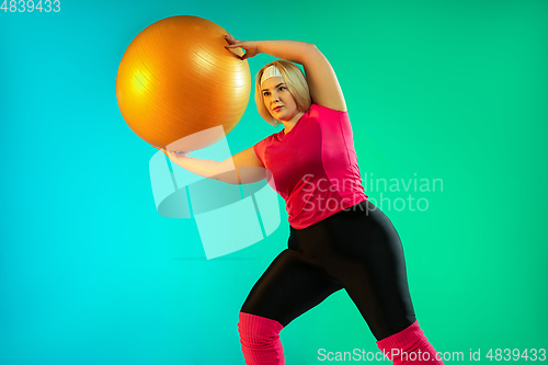 Image of Young caucasian plus size female model\'s training on gradient green background