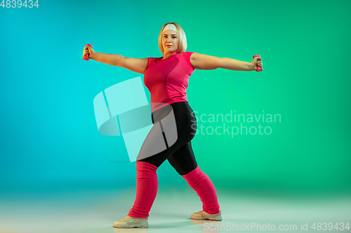 Image of Young caucasian plus size female model\'s training on gradient green background