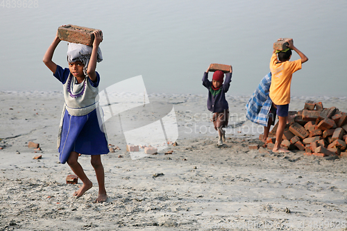 Image of Child workers carry bricks carrying it on his head in Sonakhali, West Bengal, India