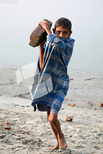 Image of Child workers carry bricks carrying it on his head in Sonakhali, West Bengal, India