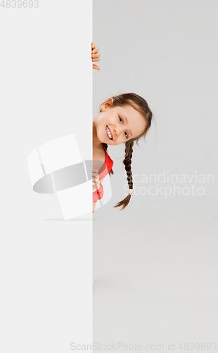 Image of Happy kid, girl isolated on white studio background. Looks happy, cheerful, sincere. Copyspace. Childhood, education, emotions concept