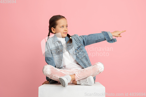 Image of Happy kid, girl isolated on pink studio background. Looks happy, cheerful, sincere. Copyspace. Childhood, education, emotions concept