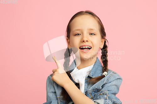 Image of Happy kid, girl isolated on pink studio background. Looks happy, cheerful, sincere. Copyspace. Childhood, education, emotions concept