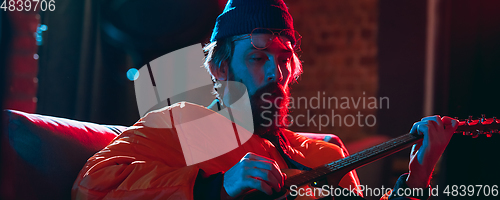 Image of Close-up of musician performing in neon light. Concept of advertising, hobby, music, festival, entertainment.