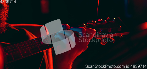 Image of Close-up of musician performing in neon light. Concept of advertising, hobby, music, festival, entertainment.