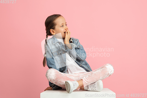 Image of Happy kid, girl isolated on pink studio background. Looks happy, cheerful, sincere. Copyspace. Childhood, education, emotions concept