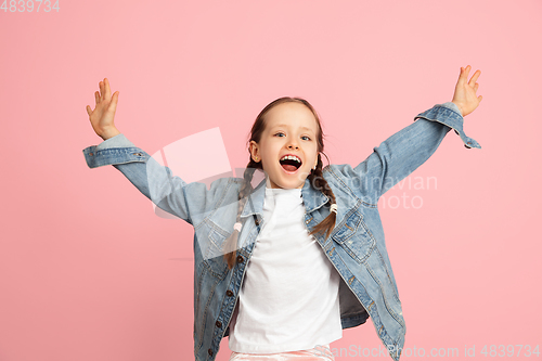 Image of Happy kid, girl isolated on pink studio background. Looks happy, cheerful, sincere. Copyspace. Childhood, education, emotions concept