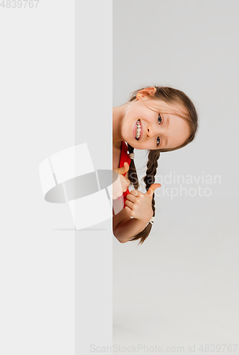 Image of Happy kid, girl isolated on white studio background. Looks happy, cheerful, sincere. Copyspace. Childhood, education, emotions concept