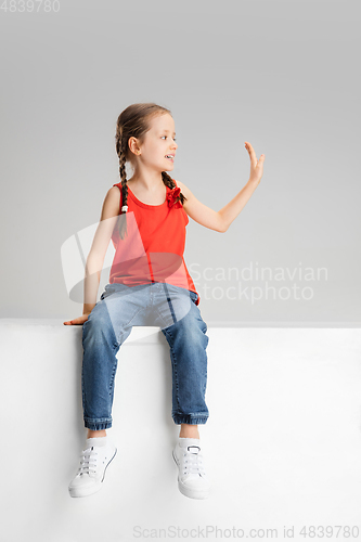 Image of Happy kid, girl isolated on white studio background. Looks happy, cheerful, sincere. Copyspace. Childhood, education, emotions concept