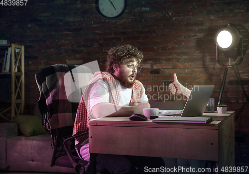 Image of Young Caucasian man talking with friend online through laptop.