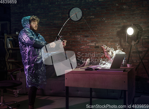 Image of Young man, fisherman catching a fish through laptop at home. Virtual reality