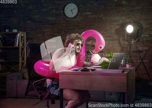 Image of Young man drinking cocktail during online meeting with friends.