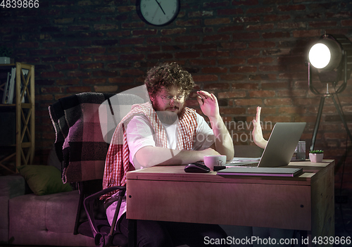 Image of Young Caucasian man talking with friend online through laptop.