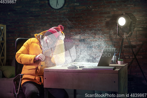 Image of Young man in bright yellow puffy jacket meeting winter on virtual video call.