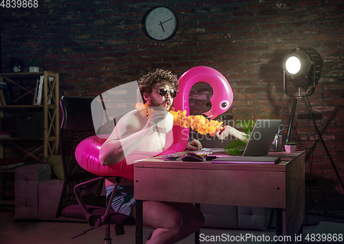 Image of Young man drinking cocktail during online meeting with friends.