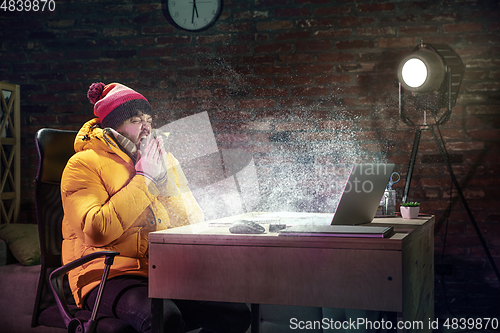 Image of Young man in bright yellow puffy jacket meeting winter on virtual video call.