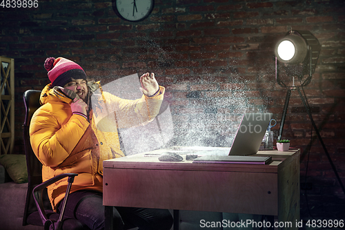 Image of Young man in bright yellow puffy jacket meeting winter on virtual video call.