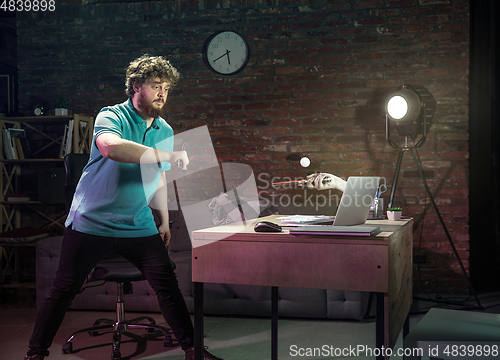 Image of Young Caucasian man playing tennis with friend online through laptop at home.