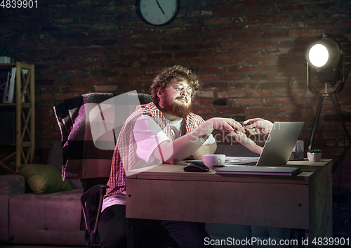 Image of Young happy Caucasian man doing a manicure online through laptop.