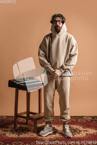 Image of Full-length portrait of man, musician isolated on light yellow background.