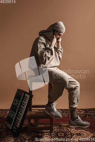 Image of Full-length portrait of man, musician isolated on light yellow background.