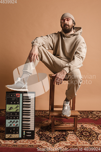 Image of Full-length portrait of man, musician isolated on light yellow background.