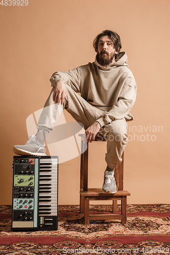 Image of Full-length portrait of man, musician isolated on light yellow background.