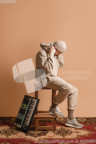 Image of Full-length portrait of man, musician isolated on light yellow background.