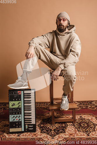 Image of Full-length portrait of man, musician isolated on light yellow background.
