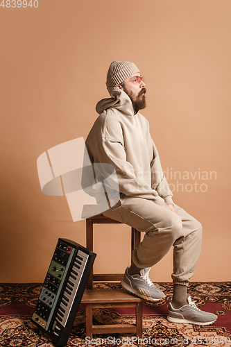Image of Full-length portrait of man, musician isolated on light yellow background.