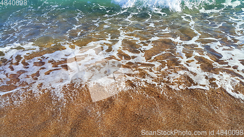 Image of Clear sea water with white foam in the coastal sand