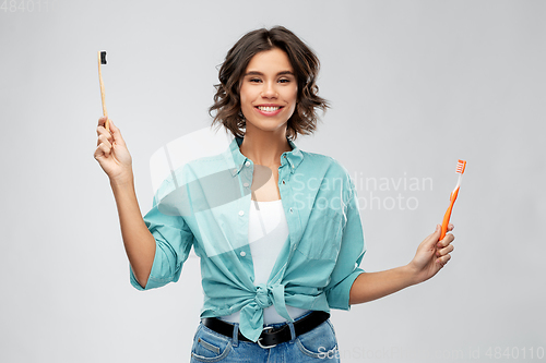 Image of woman comparing wooden and plastic toothbrush