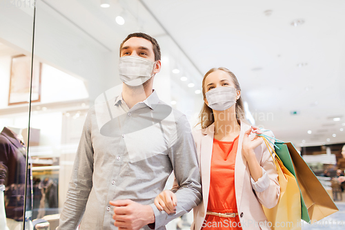 Image of couple in medical masks with shopping bags in mall