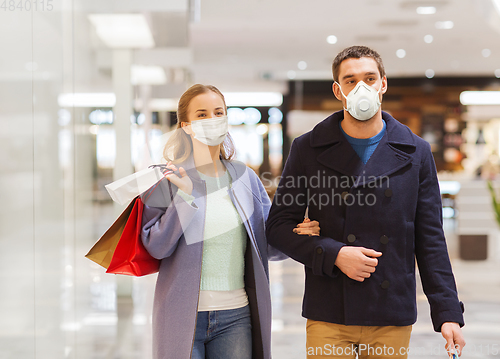 Image of couple in medical masks with shopping bags in mall