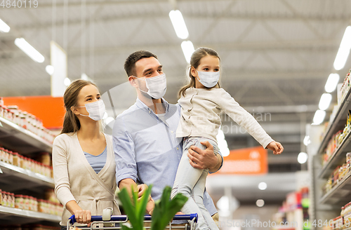 Image of family with shopping cart in masks at supermarket