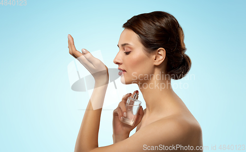 Image of happy woman smelling perfume from her wrist