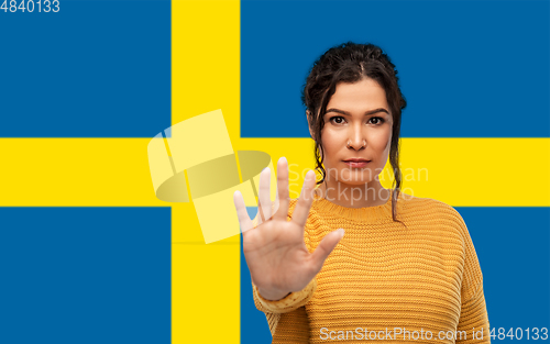 Image of woman showing stop gesture over flag of sweden