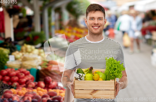 Image of happy man with food in wooden box at street market