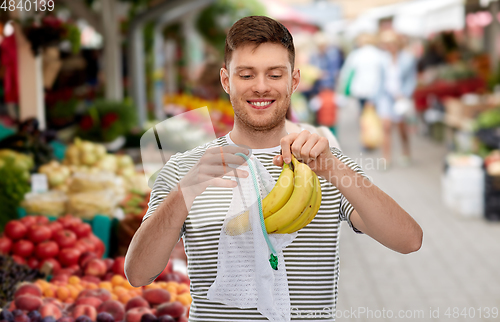 Image of man with bananas and string bag at street market