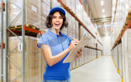 Image of happy delivery girl with clipboard at warehouse