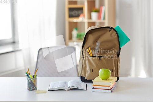 Image of books, apple and school supplies on table at home