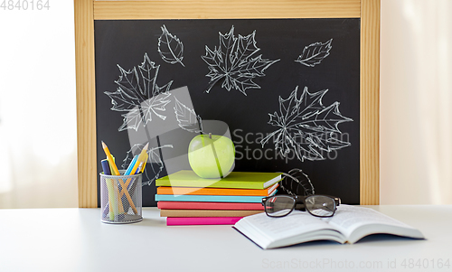 Image of books, apple and school supplies on table at home